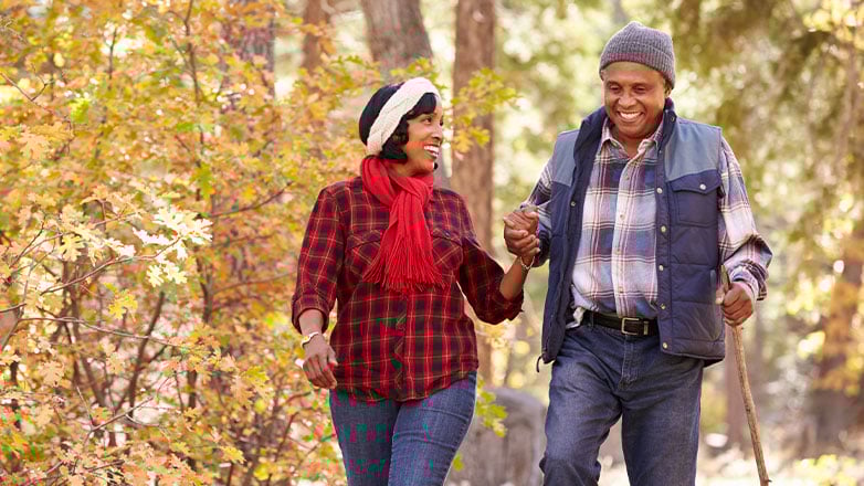 older couple hiking through the autumn woods