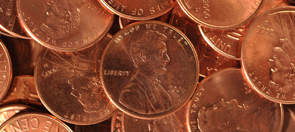 A collection of copper-colored US pennies, stacked on top of each other, showing the head of Abraham Lincoln and the inscriptions "Liberty", "In God We Trust", and the year minted.