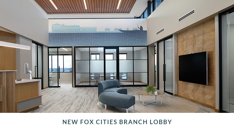 Lobby inside the new Fox Cities location, featuring bright lighting, teller line, a couch and a large flat screen TV.